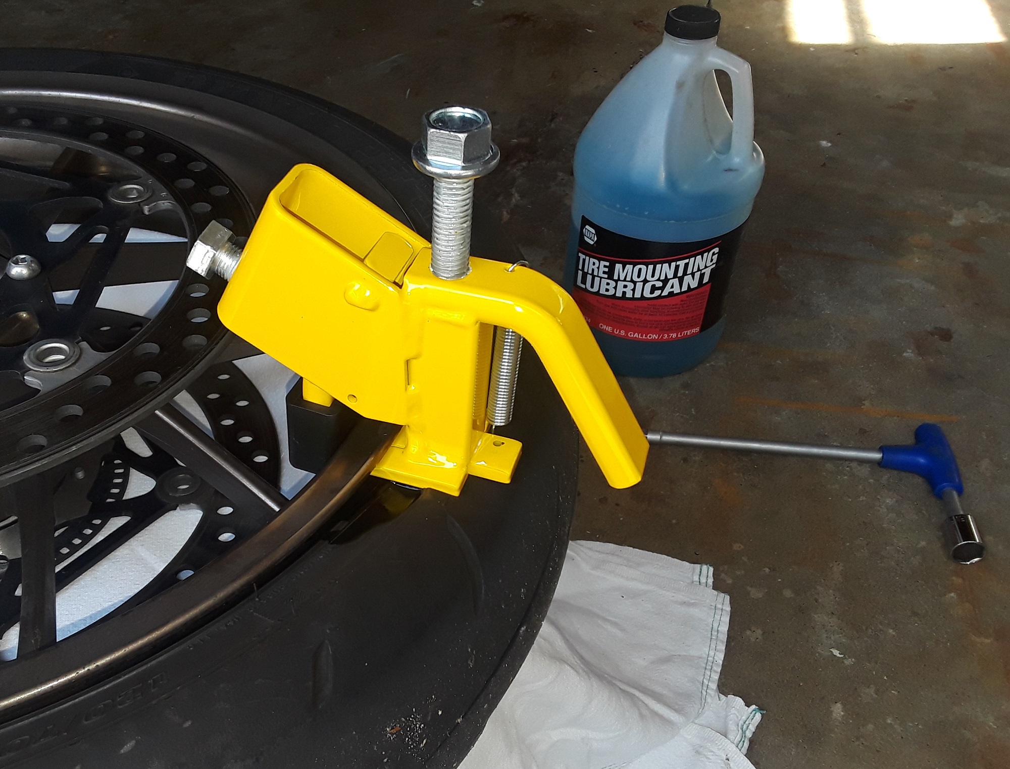 Clamp the BeadBuster to the rim with the bottom slipped between the tire and the rim