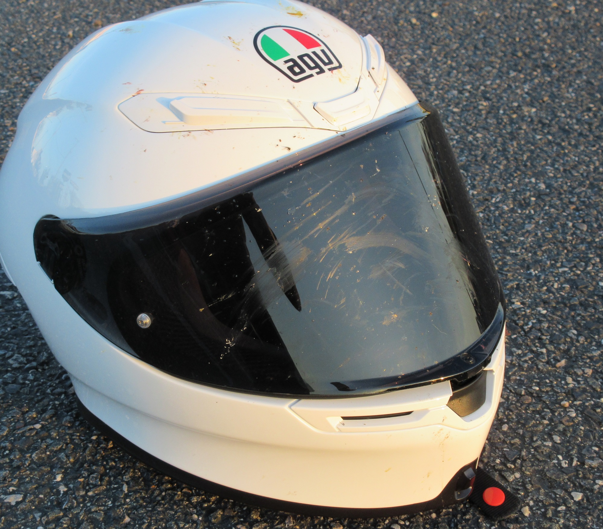 white AGV K6 S helmet with tinted visor, both covered with splattered insects
