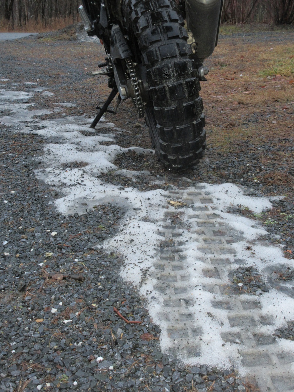 close shot of knobby rear tire on the BMW G 310 GS and its track in the mud and a scrap of snow