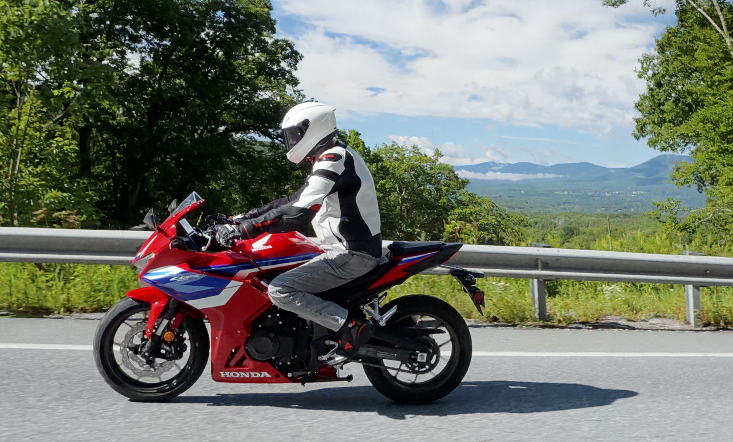 rider on the red CBR500R on the road, mountains in the distant background
