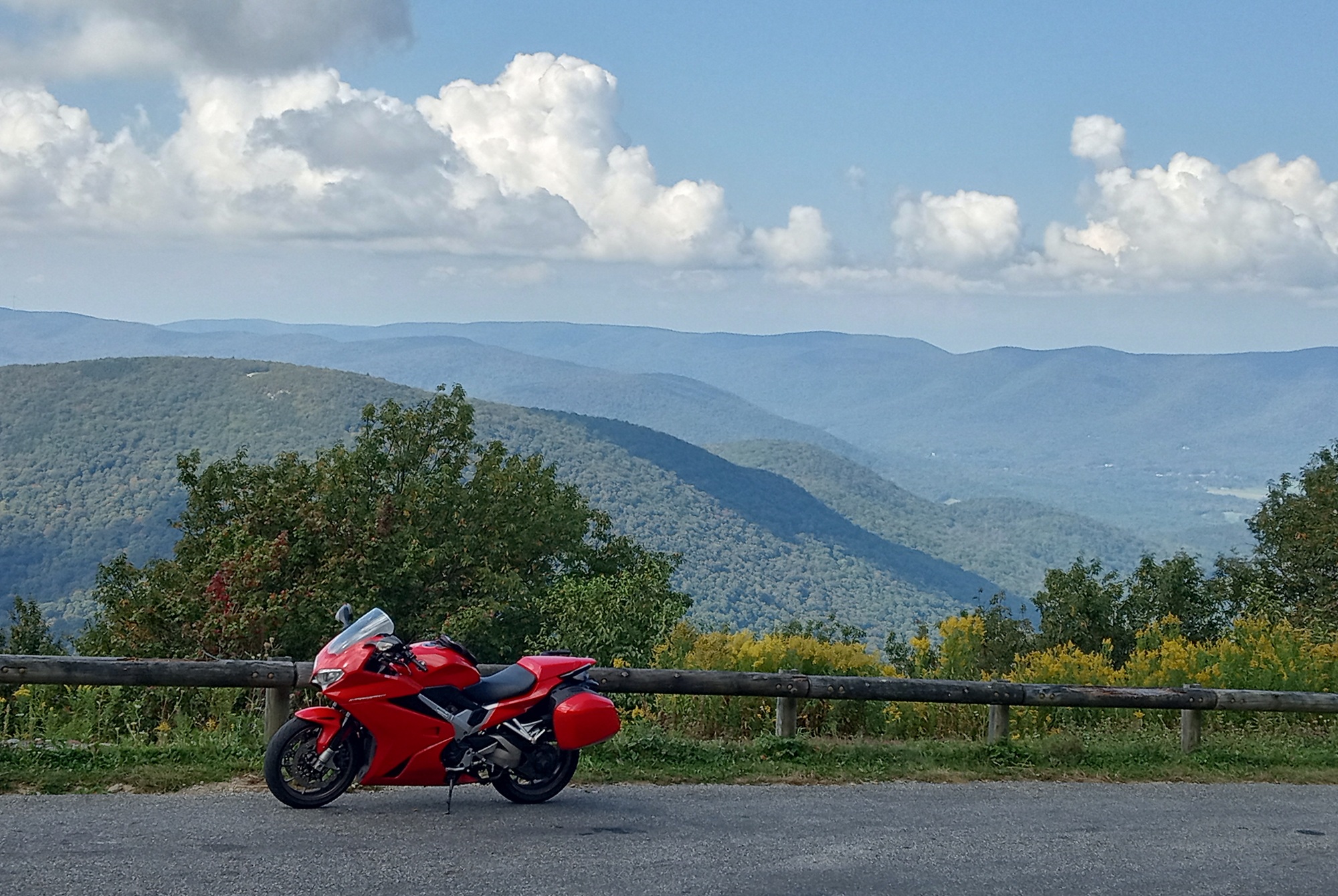 red Honda VFR800 parked at an overlook with mountains in the distance, leaves just beginning to turn