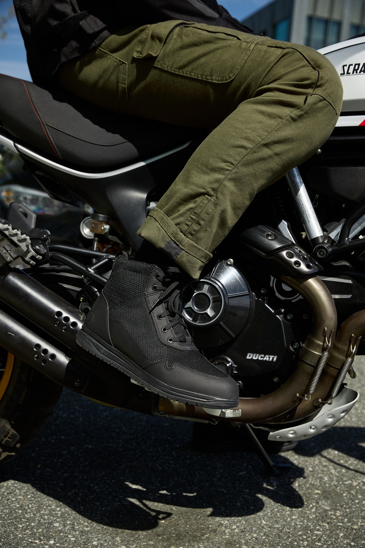 rider sitting on a motorcycle wearing green cargo pants and low black boots
