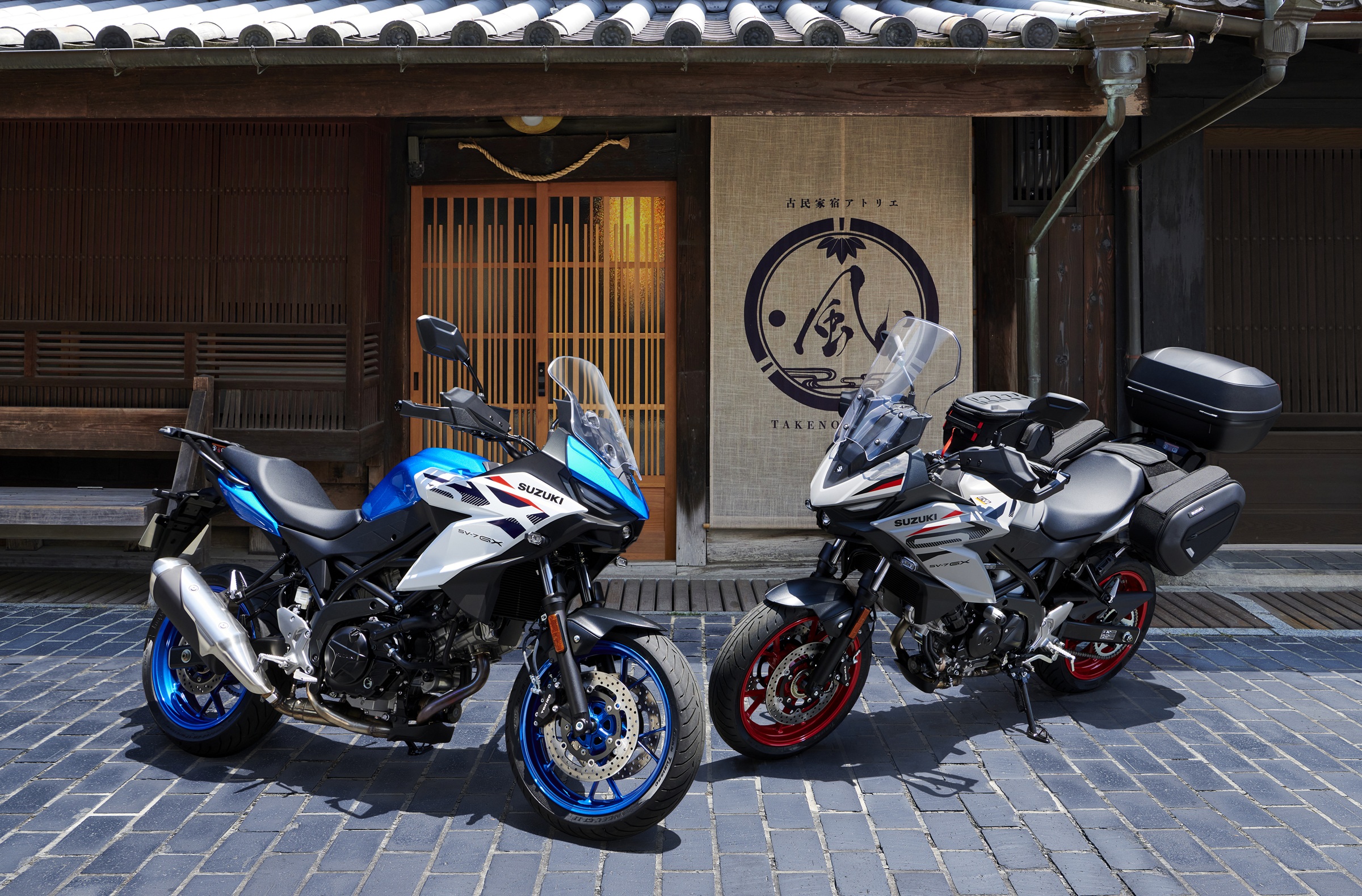 the blue and white version and the beige-gray version of the SV-7GX parked side by side, the latter fitted with touring accessories