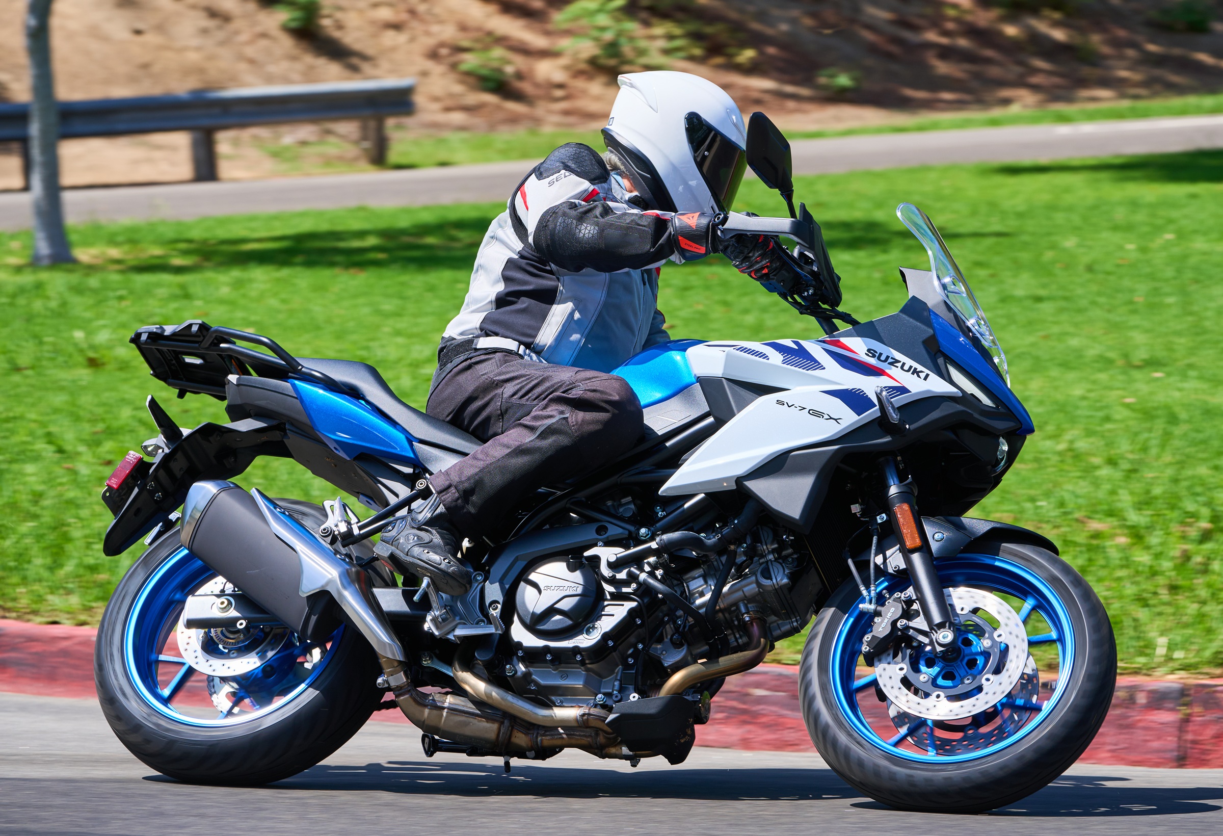 riding the blue and white SV-7GX through a curve in a park