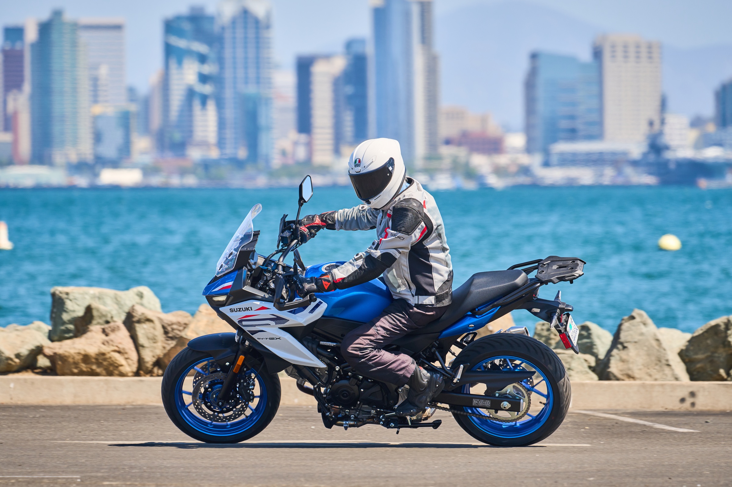 riding the blue and white SV-7GX in front of the bay with the San Diego skyline in the background on a sunny day