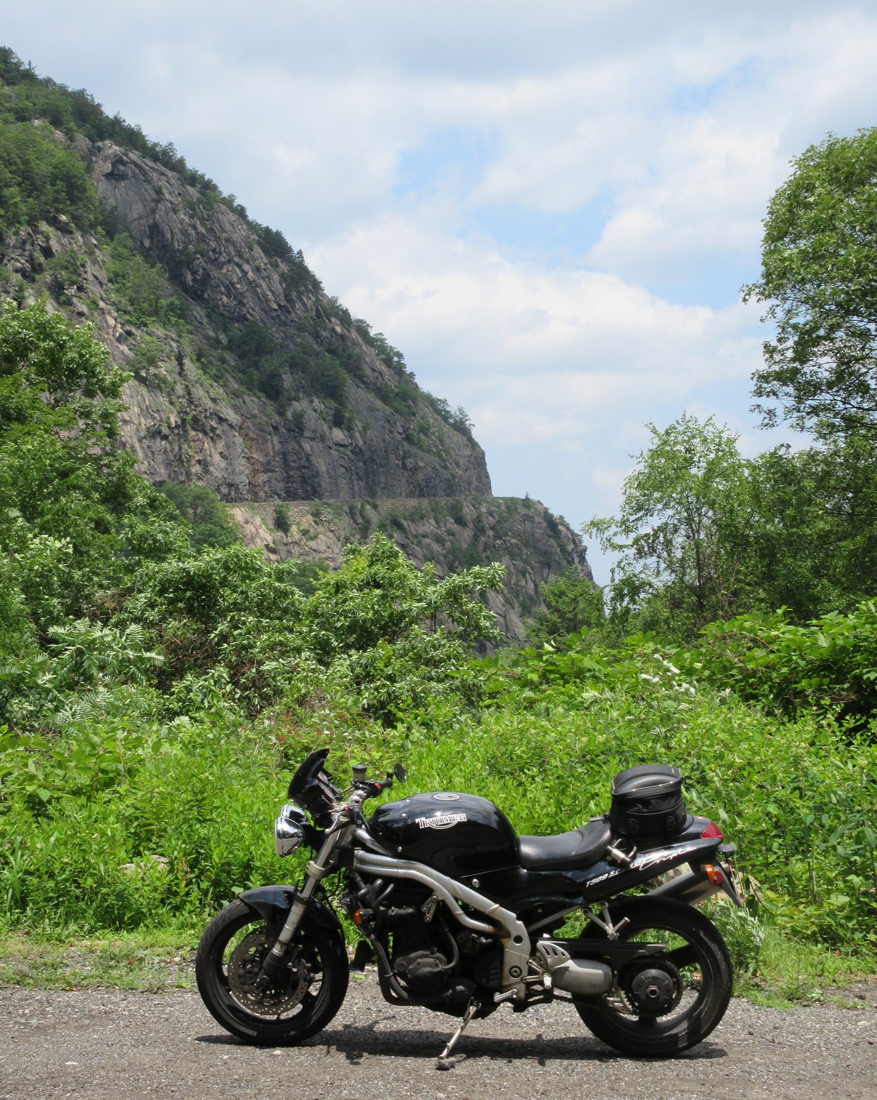 the black 1997 Triumph Speed Triple at a pull off with the cliff of Storm King Mountain in the background