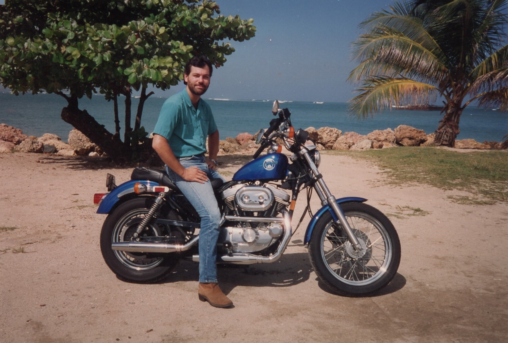 author at age 35 sitting on a blue Sportster on a beach in Puerto Rico