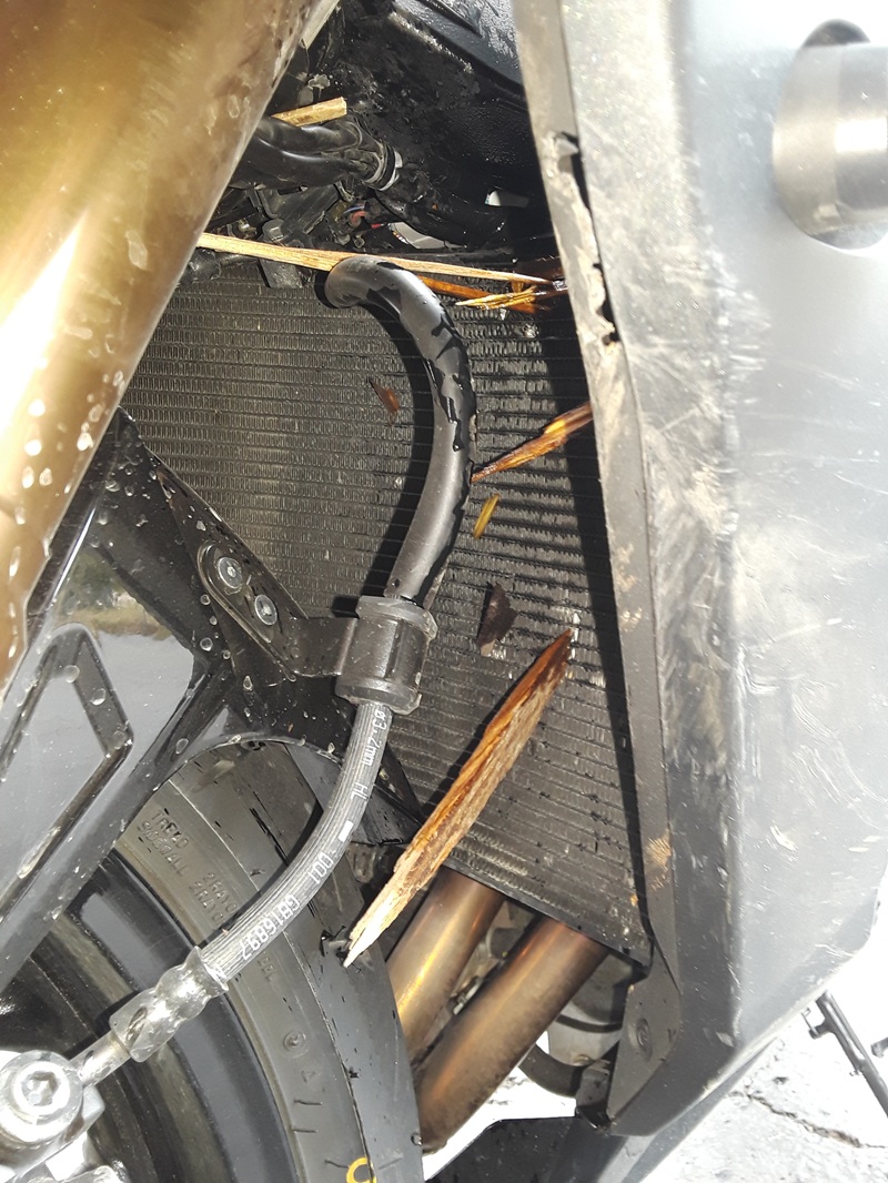 close view of shards of wood sticking into the Suzuki's radiator, dripping fluid