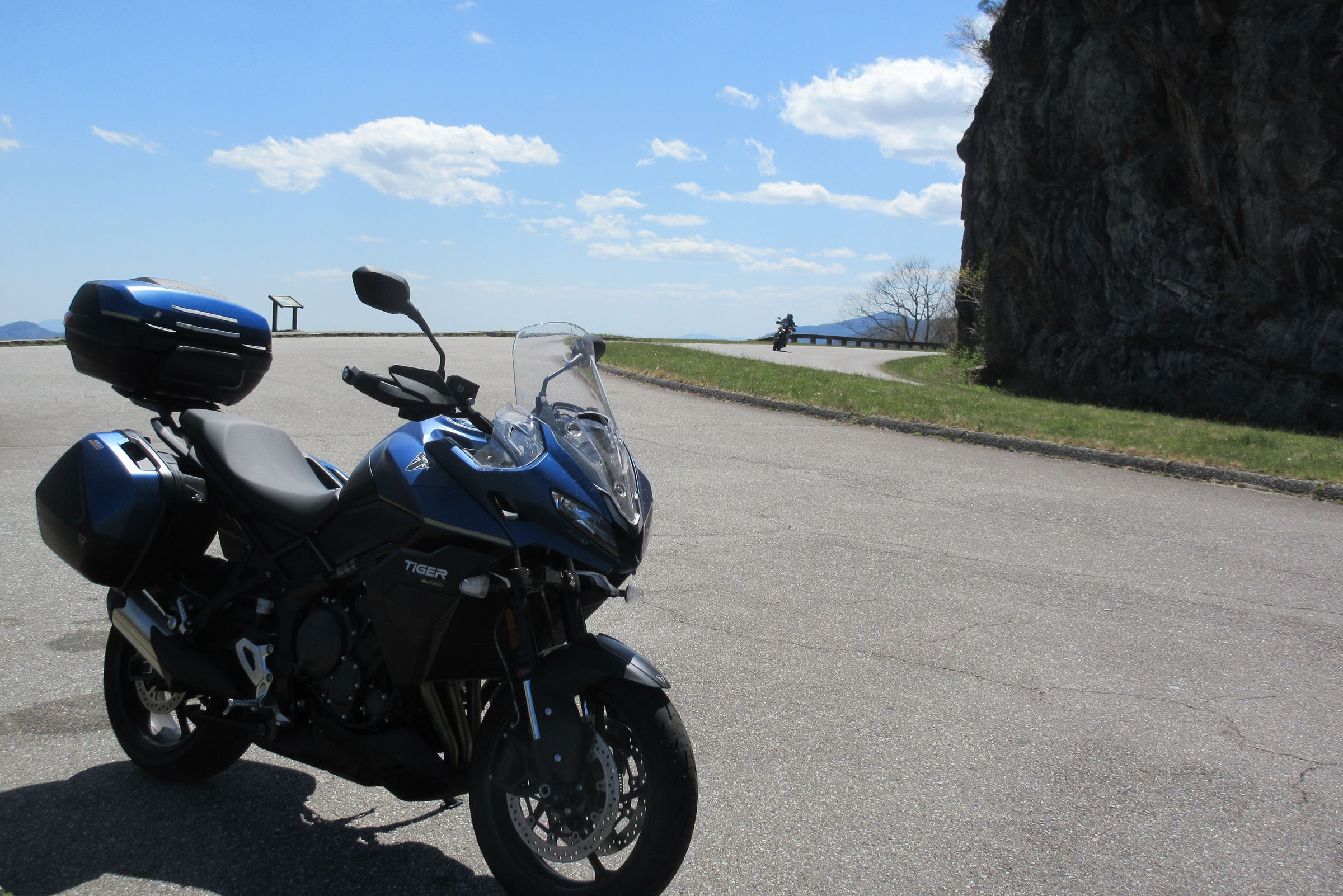 blue Triumph Tiger Sport 800 Tour parked at an overlook in the mountains along the Blue Ridge Parkway as another motorcycle rides by