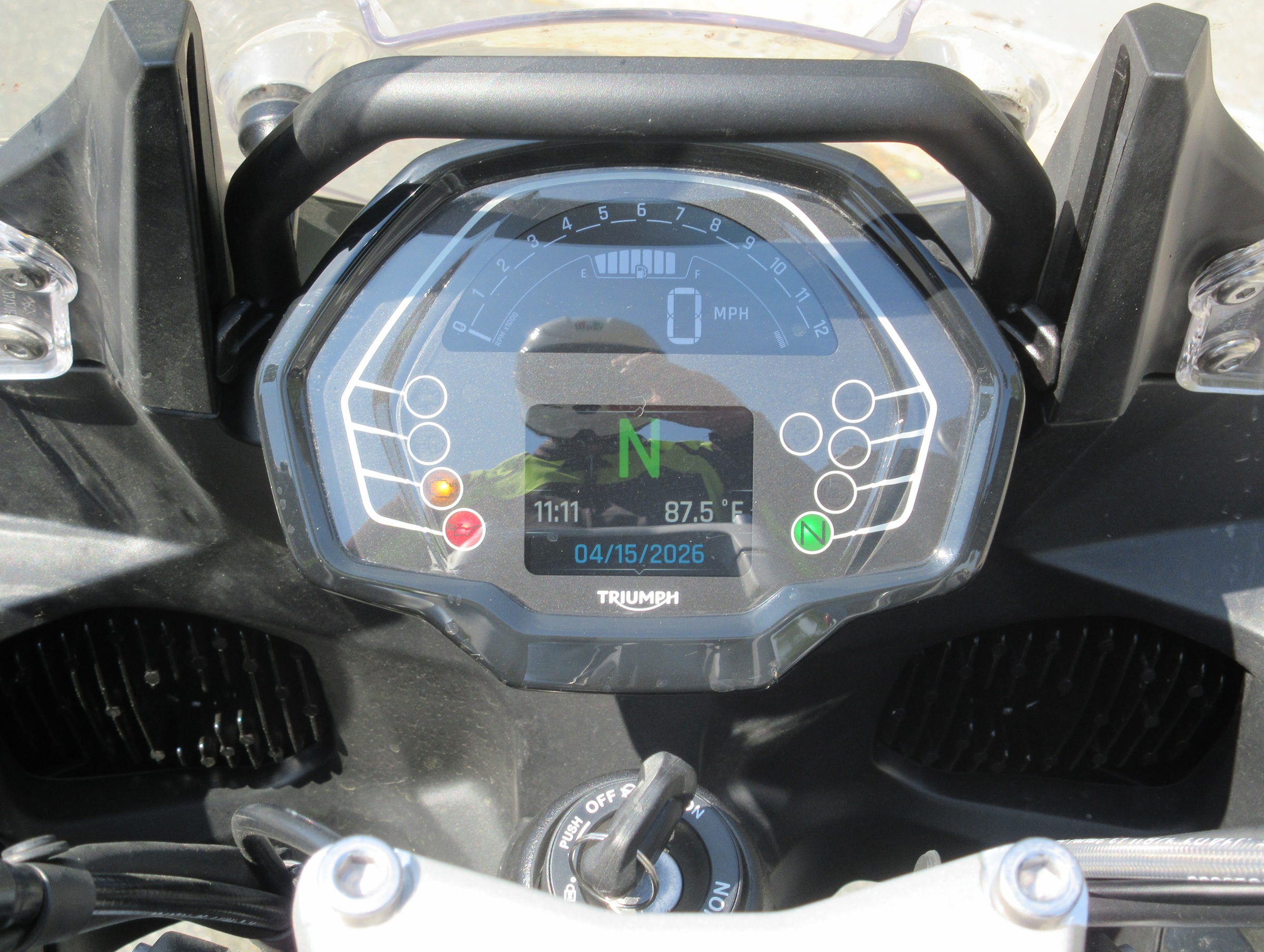 view of the digital display on the Triumph, showing the reflection of the rider taking the photo