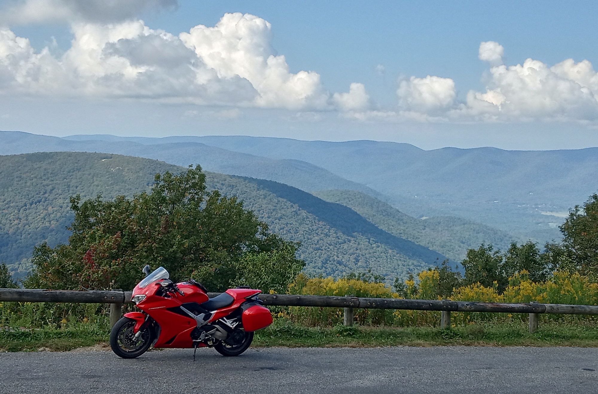 red Honda VFR800 parked at an overlook with mountains in the distance