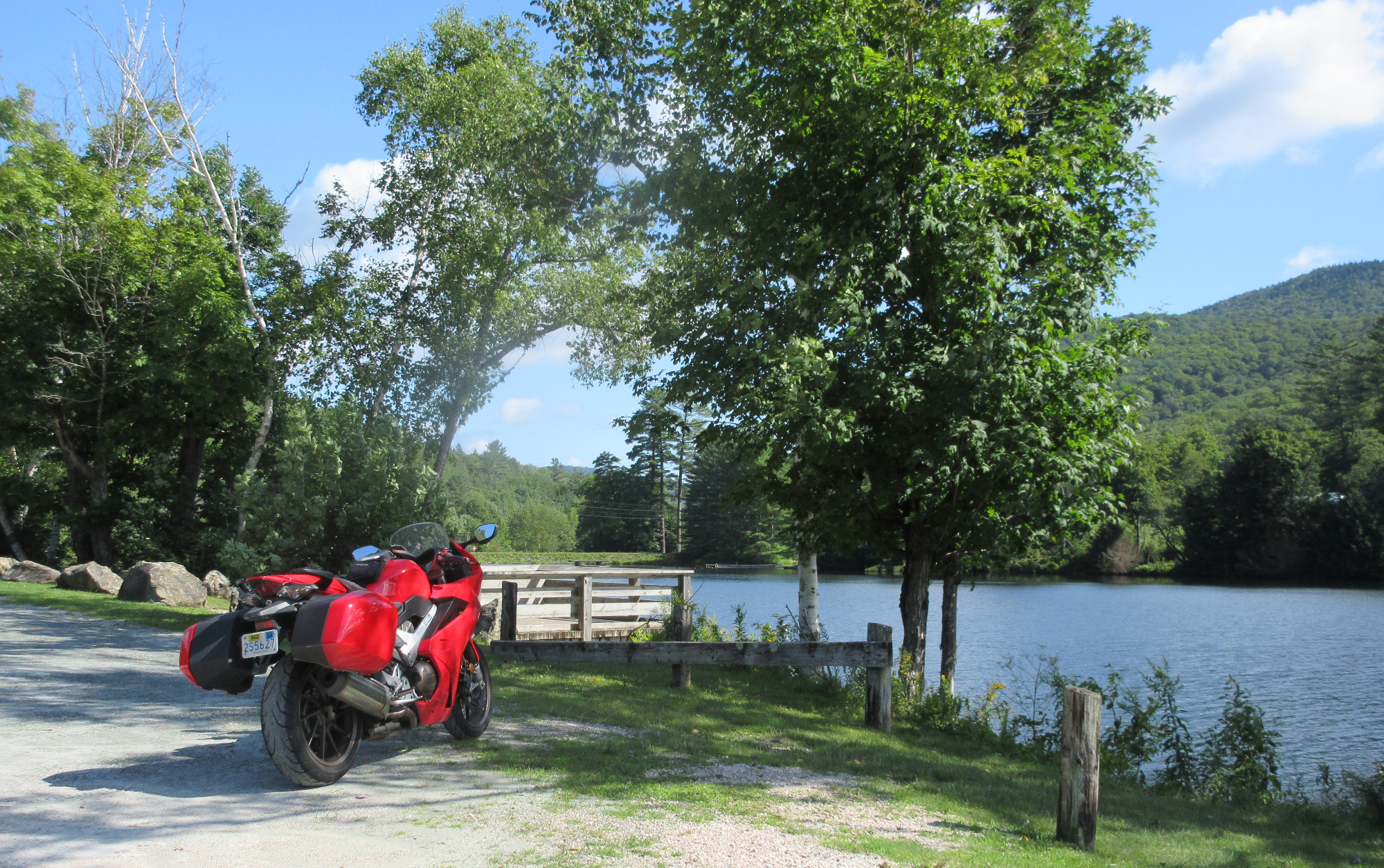 Red Honda VFR800 parked by a lake on a sunny day in Vermont