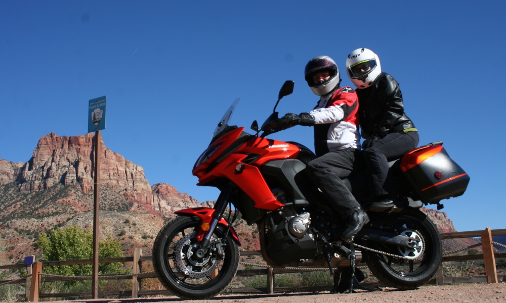 Lance and Ivonne on a Kawasaki Versys 1000 in front of a red mountain in Utah