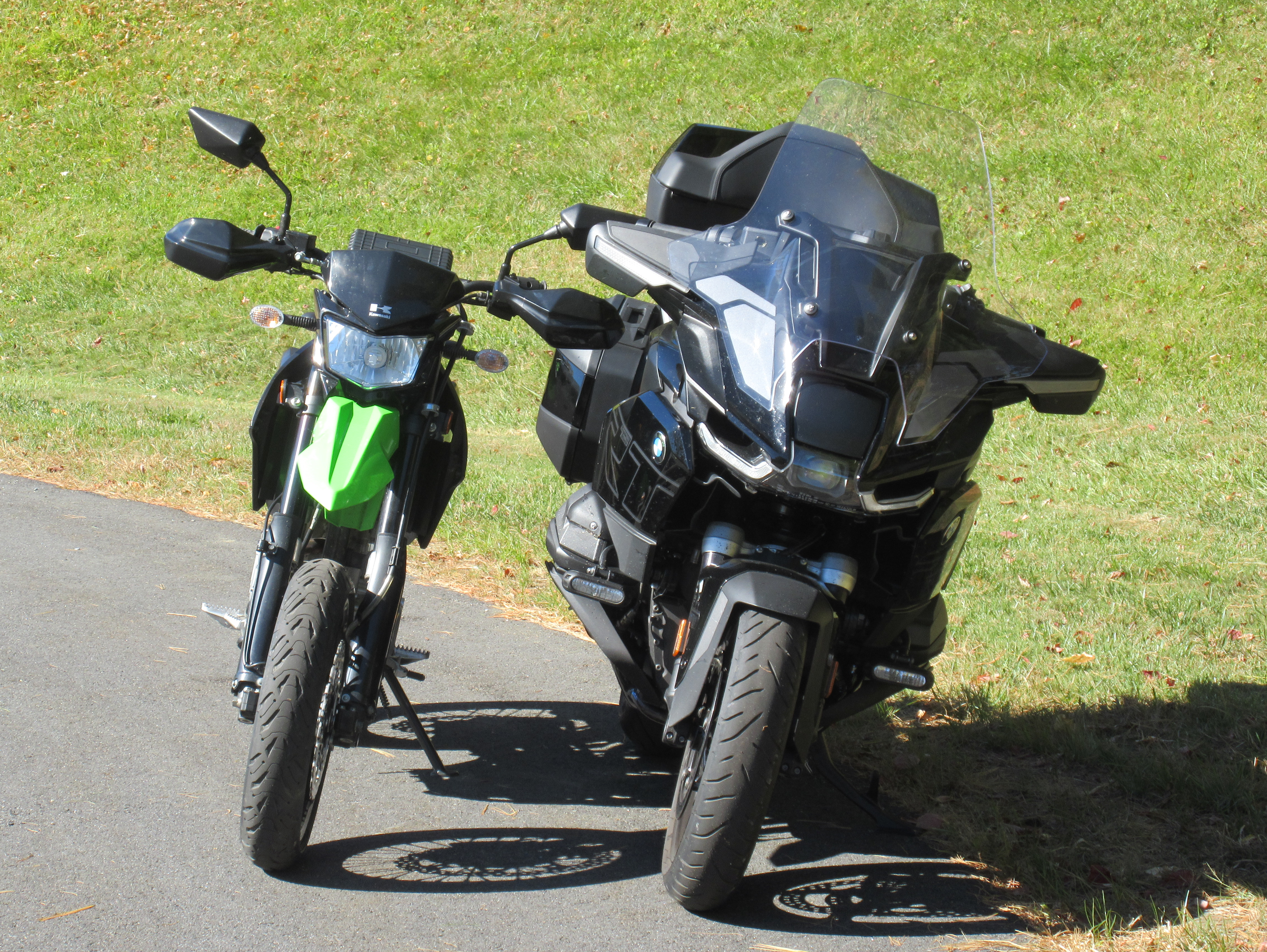 front view of the small, narrow, supermoto Kawasaki parked beside the full-size BMW touring motorcycle